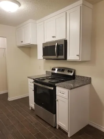 a view of kitchen with stainless steel appliances granite countertop cabinets and wooden floor