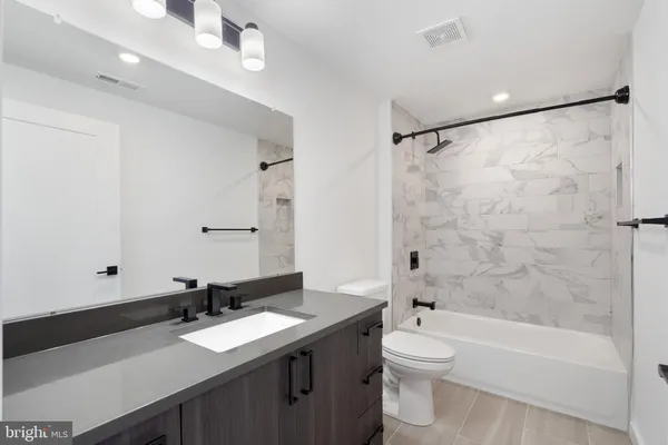a bathroom with a granite countertop sink a toilet a mirror and shower