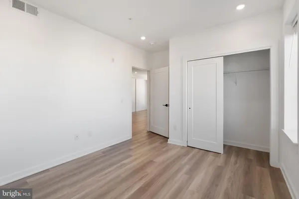 a view of an empty room with wooden floor and closet