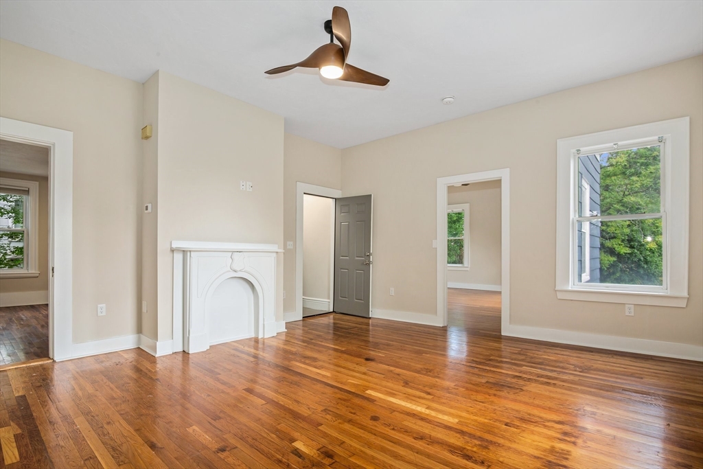 a view of empty room with wooden floor and fan