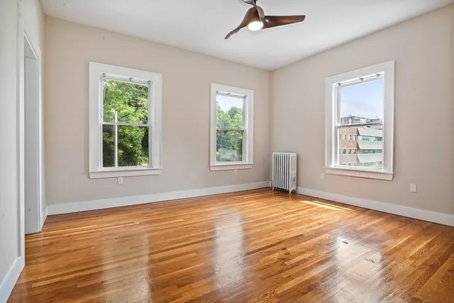 a view of an empty room with a window and wooden floor