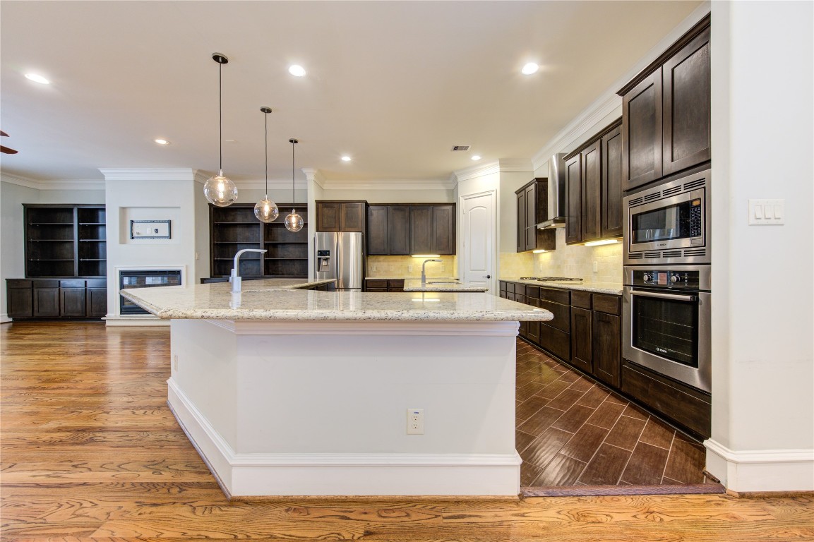 5226 Kiam Street, Unit 1015 Houston, TX 77007 - Photo 27 of 49 a view of kitchen with stainless steel appliances kitchen island granite countertop a stove top oven a sink and a wooden floors