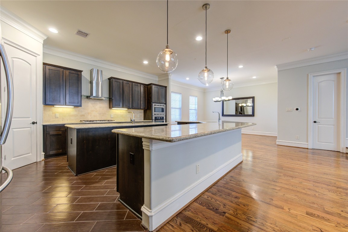 5226 Kiam Street, Unit 1015 Houston, TX 77007 - Photo 34 of 49 a large kitchen with stainless steel appliances kitchen island granite countertop a stove a sink a refrigerator and a wooden floor