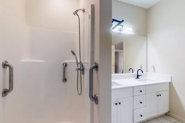 a bathroom with a double vanity sink a mirror and shower