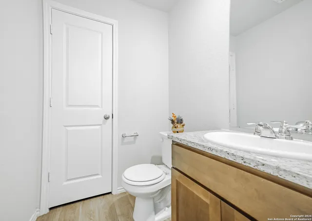 a bathroom with a granite countertop sink mirror vanity and toilet