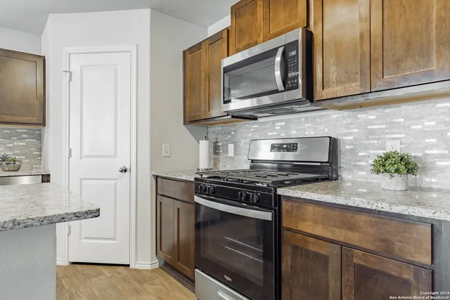 a kitchen with stainless steel appliances granite countertop white cabinets and a stove top oven