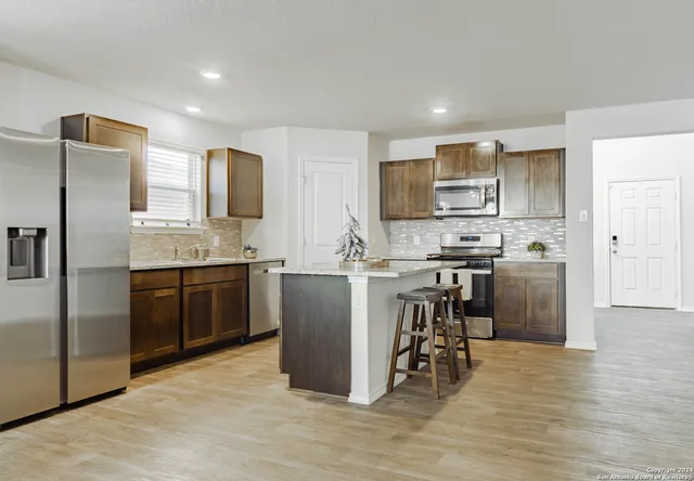 a kitchen with kitchen island a counter top space stainless steel appliances and cabinets