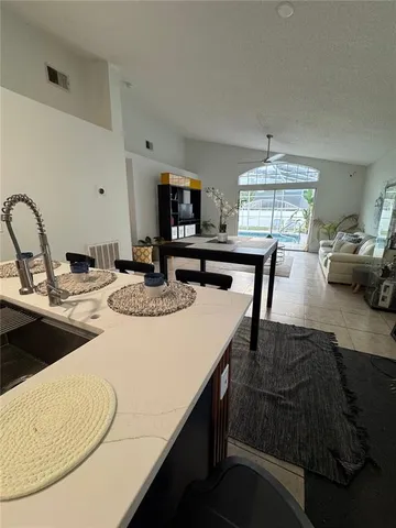 a kitchen with kitchen island a stove a sink a dining table and chairs