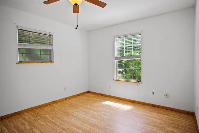 a view of an empty room with window and wooden floor