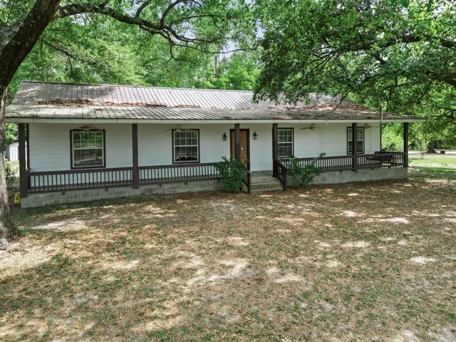 a view of a house with a yard and large tree