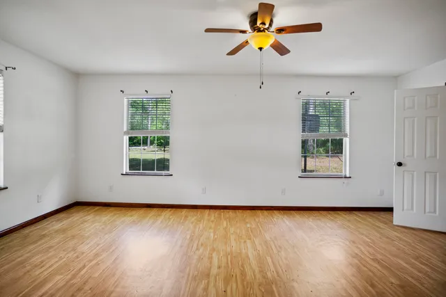 an empty room with wooden floor and windows