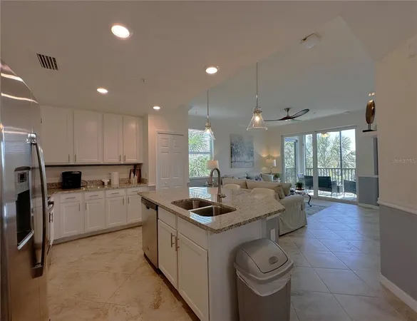 a kitchen with stainless steel appliances granite countertop a sink a stove a refrigerator cabinets and chairs