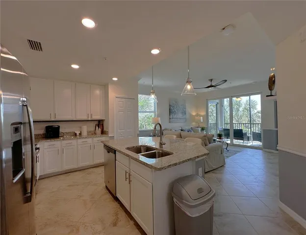 a kitchen with stainless steel appliances granite countertop a sink a stove a refrigerator cabinets and chairs