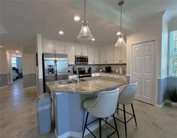 a kitchen with stainless steel appliances granite countertop a stove a sink a microwave a center island and chairs