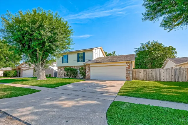 a view of a house with a yard and a large tree