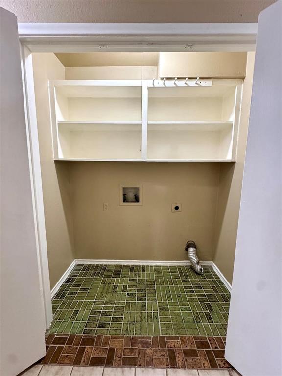 13357 Kit Lane Dallas, TX 75240 - Photo 16 of 26 Dedicated laundry area featuring built-in shelving, a wall-mounted hook rack, and a green and brown tile floor