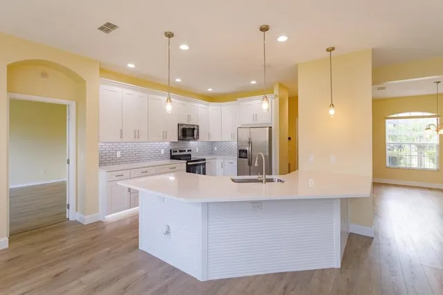 a large kitchen with stainless steel appliances kitchen island a large counter top and a wooden floors