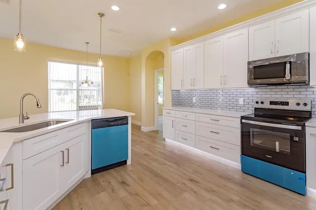 a kitchen with stainless steel appliances granite countertop a stove a sink and a microwave