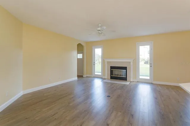 a view of an empty room with wooden floor fireplace and a window