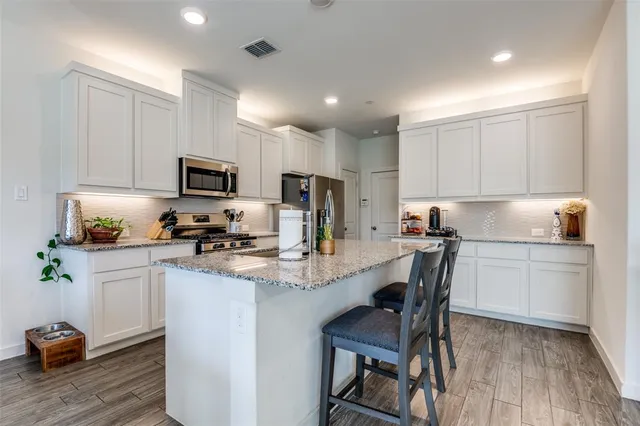 a kitchen with kitchen island granite countertop a sink cabinets and wooden floor