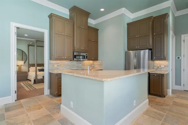 a kitchen with kitchen island granite countertop a sink stove and refrigerator