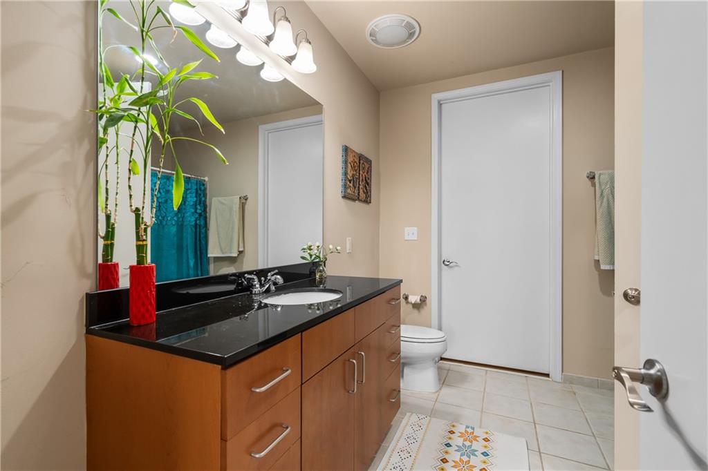 711 Cosmopolitan Drive Northeast, Unit 517 Atlanta, GA 30324 - Photo 19 of 29 a bathroom with a granite countertop sink a mirror and a shower