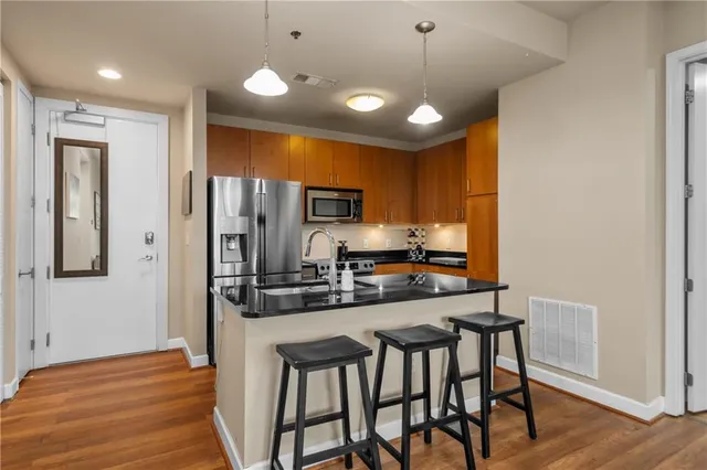 a kitchen with stainless steel appliances a dining table chairs refrigerator and microwave