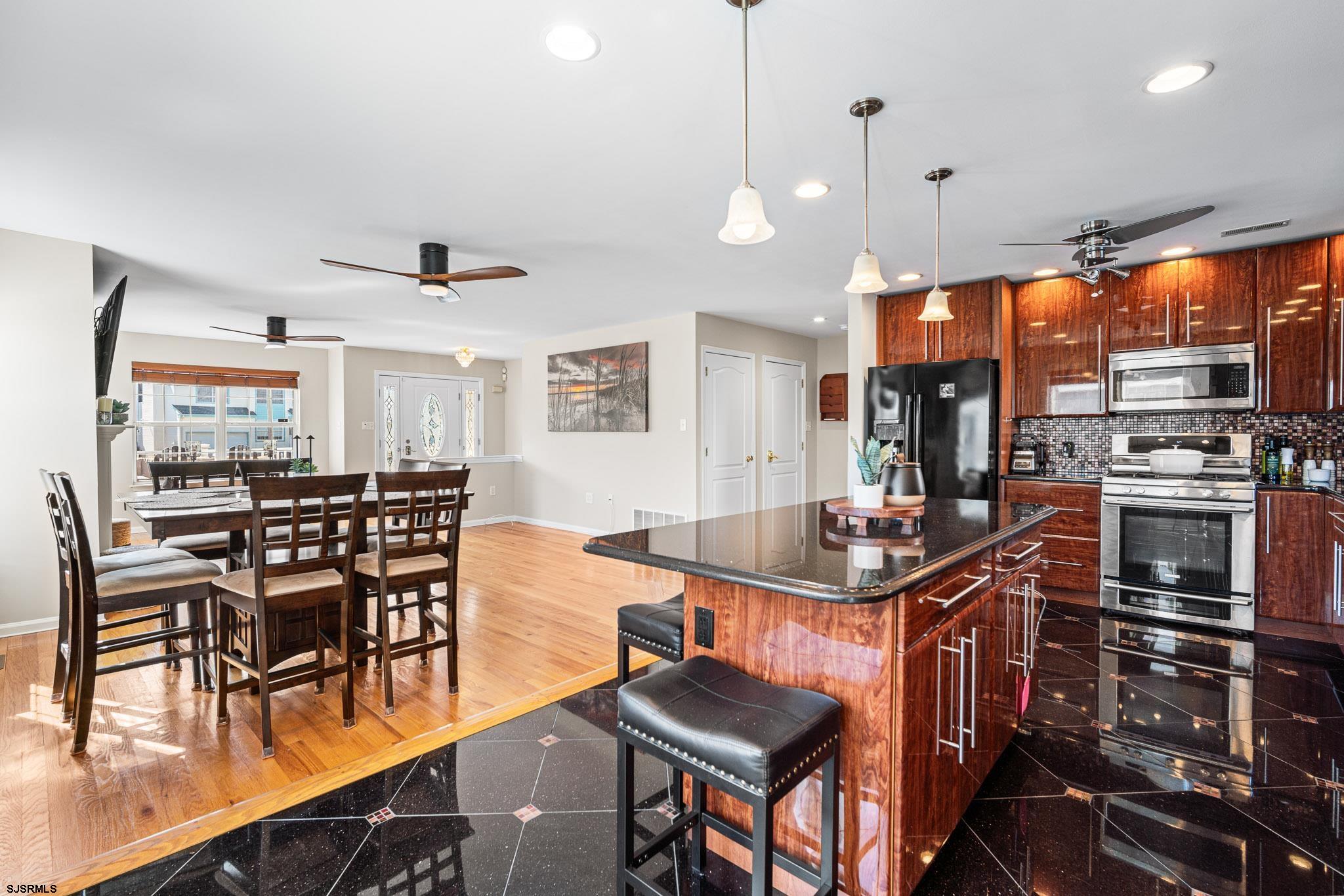 5 Collette Circle Brigantine, NJ 08203 - Photo 12 of 36 a kitchen with stainless steel appliances kitchen island granite countertop a stove a sink a dining table and chairs with wooden floor