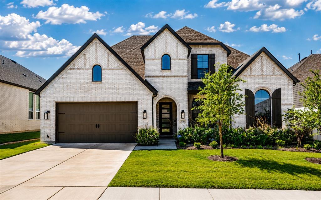 2150 Charming Frg Road Forney, TX 75126 - Photo 2 of 40 Brick exterior with black trim, arched windows, dark-paneled garage door, and a concrete driveway