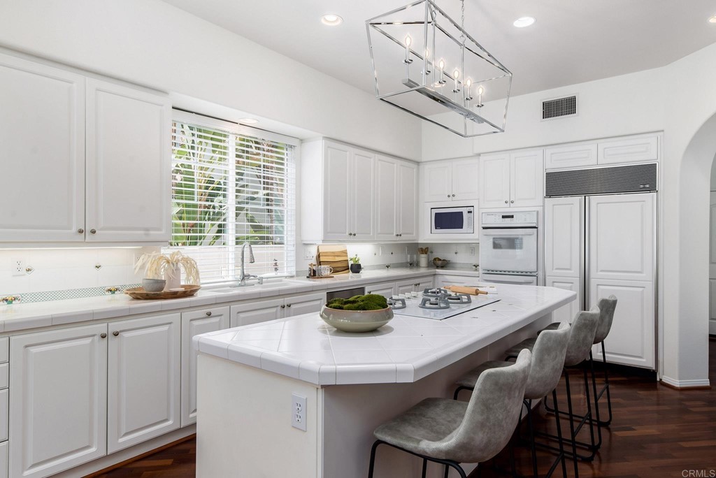 1368 Corvidae Street Carlsbad, CA 92011 - Photo 7 of 38 a kitchen with stainless steel appliances granite countertop a sink a stove a dining table and chairs