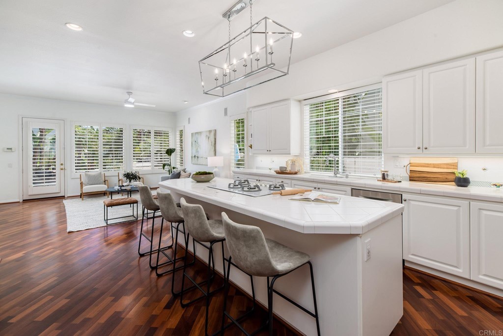1368 Corvidae Street Carlsbad, CA 92011 - Photo 10 of 38 a kitchen with stainless steel appliances granite countertop a stove a sink dishwasher a dining table and chairs with wooden floor