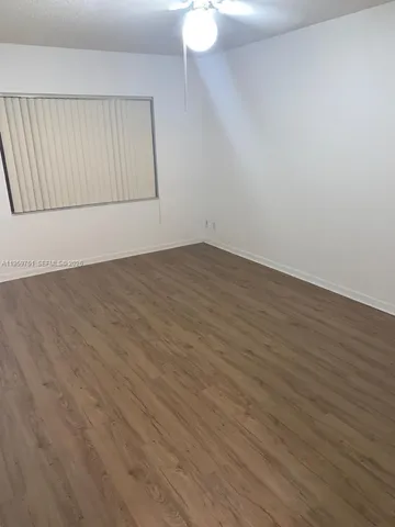 a view of an empty room with wooden floor and cabinet