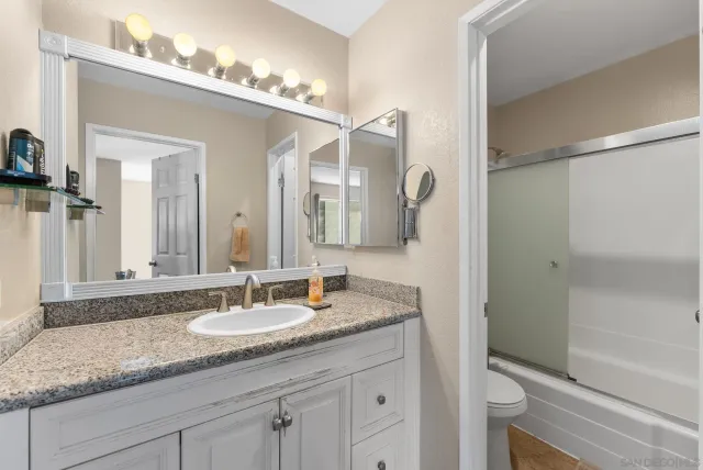 a bathroom with a granite countertop sink a mirror and a shower