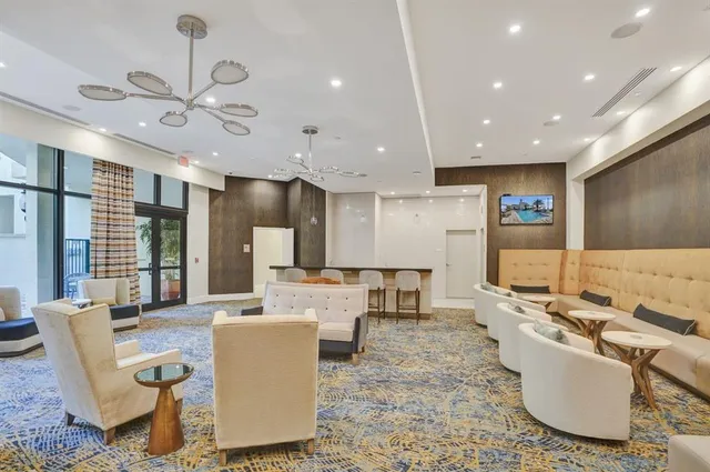 a living room with couches kitchen view and a chandelier