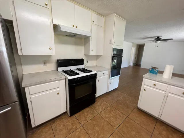 a kitchen with white cabinets and appliances
