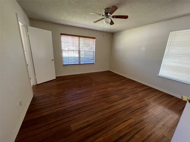 a view of empty room with wooden floor and fan