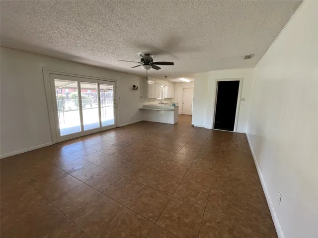 an empty room with windows and chandelier fan