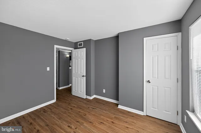 a view of an empty room with wooden floor and closet