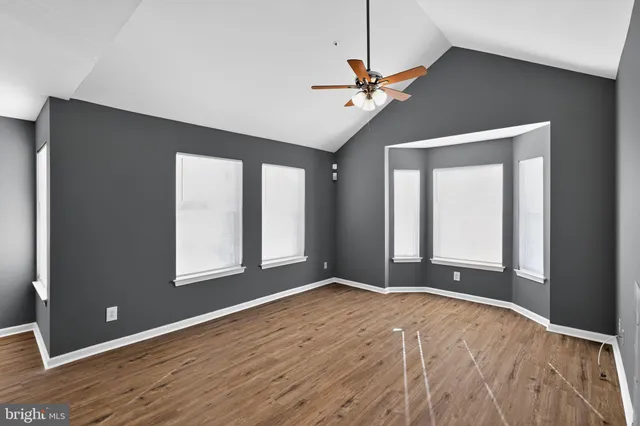 a view of an empty room with window and chandelier fan