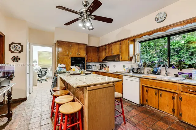 a kitchen with stainless steel appliances kitchen island granite countertop a table chairs sink and cabinets