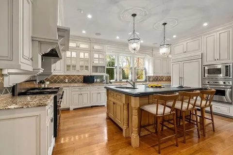 a kitchen with stainless steel appliances kitchen island granite countertop a stove a sink a refrigerator and a dining table with wooden floor