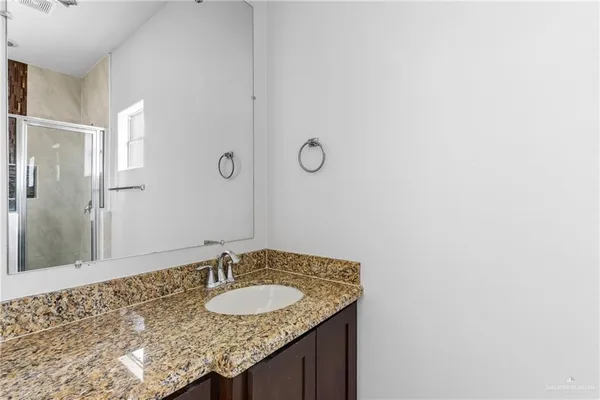 a bathroom with a granite countertop sink and a mirror