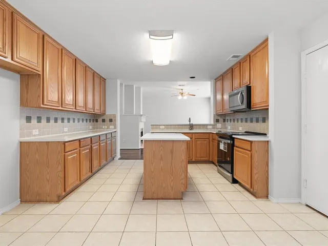a kitchen with stainless steel appliances granite countertop a stove top oven a sink dishwasher and white cabinets