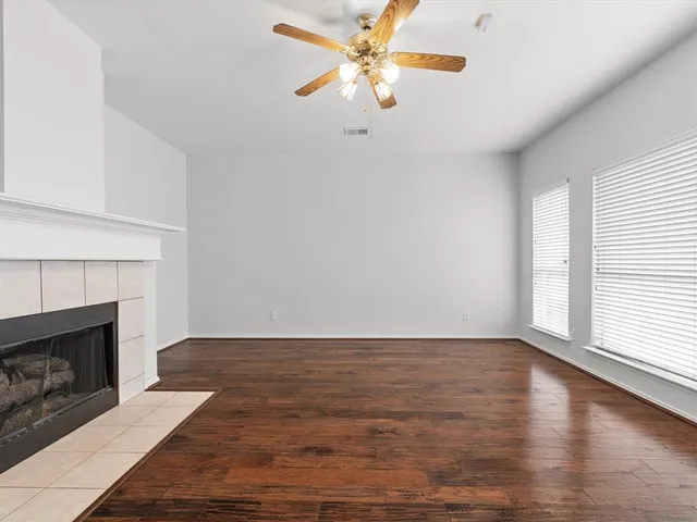 a view of a livingroom with a fireplace a ceiling fan and wooden floor