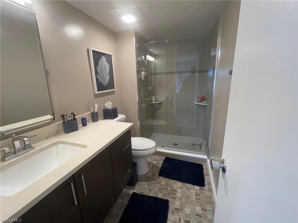 309 Goodlette-Frank Road, Unit 306A Naples, FL 34102 - Photo 13 of 19 a bathroom with a double vanity sink a toilet a shower and a mirror