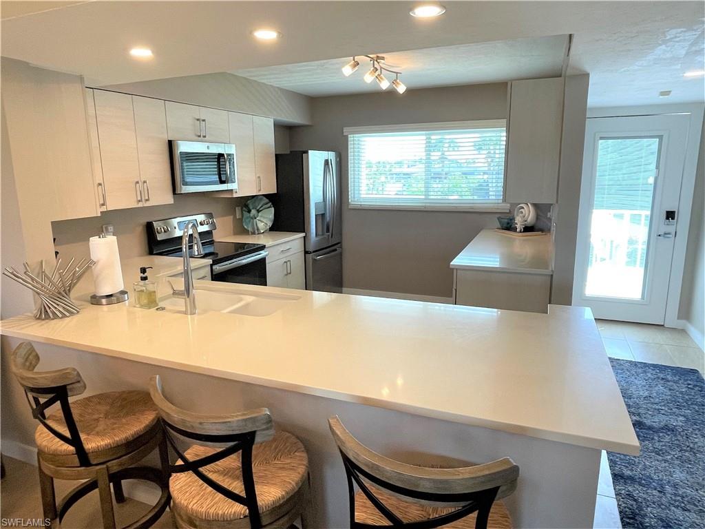309 Goodlette-Frank Road, Unit 306A Naples, FL 34102 - Photo 3 of 19 a view of kitchen island dining table and chairs
