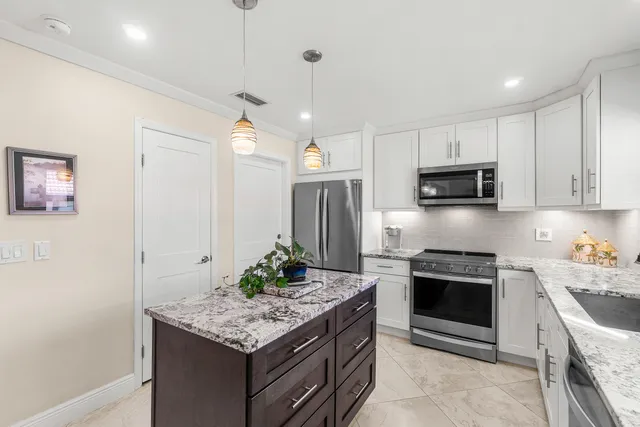 a kitchen with stainless steel appliances kitchen island granite countertop a stove sink and refrigerator
