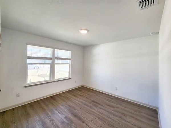 an empty room with wooden floor and windows