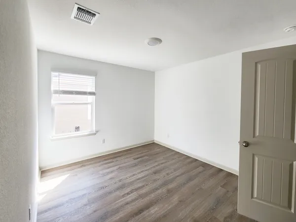 an empty room with wooden floor and windows