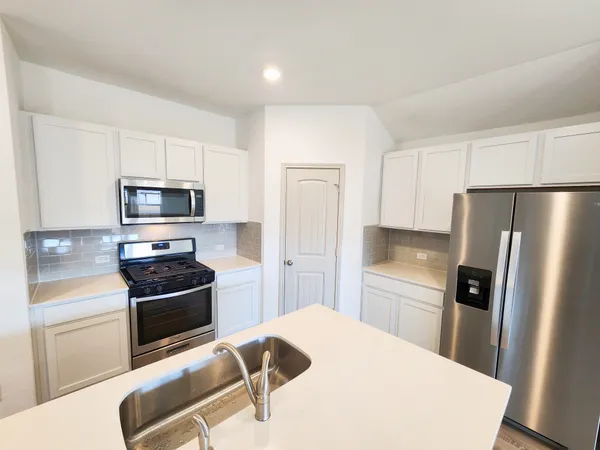a kitchen with stainless steel appliances a refrigerator stove and microwave